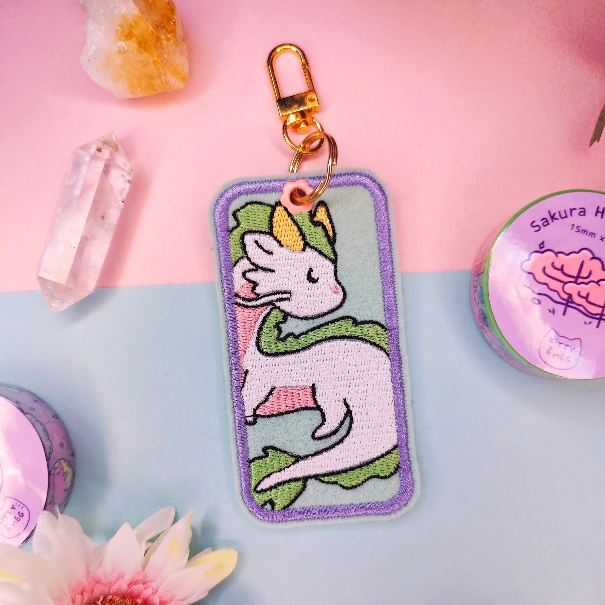 Keychain with haku ghibli on a pink and blue gradient background with flowers and crystals.