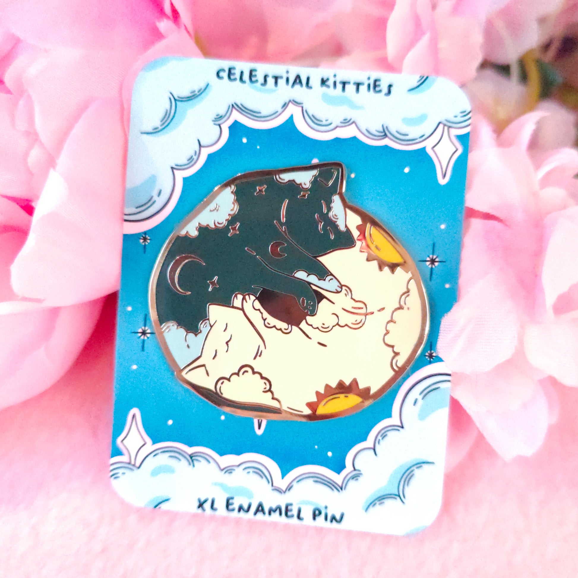 Enamel pin with celestial design on a blue card, surrounded by pink flowers. shipped from eu