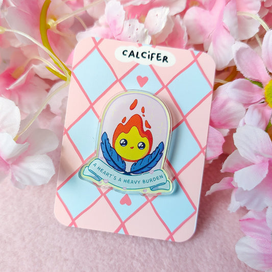 Calcifer-inspired flame spirit acrylic pin with quote ‘A heart’s a heavy burden’ on backing card