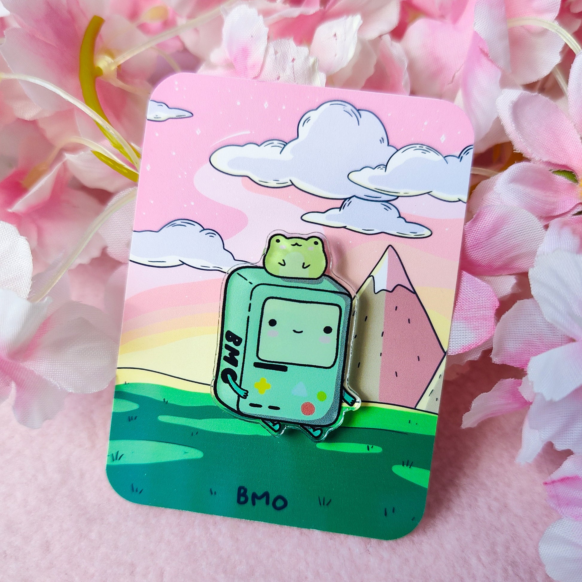 Cute BMO-inspired acrylic pin with a frog on his head, displayed on art backing card