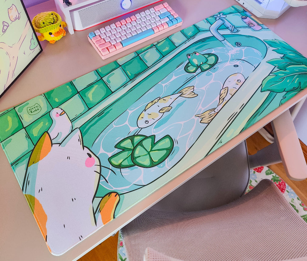 Desk setup with a colorful desk mat featuring cartoon fish and lily pads.