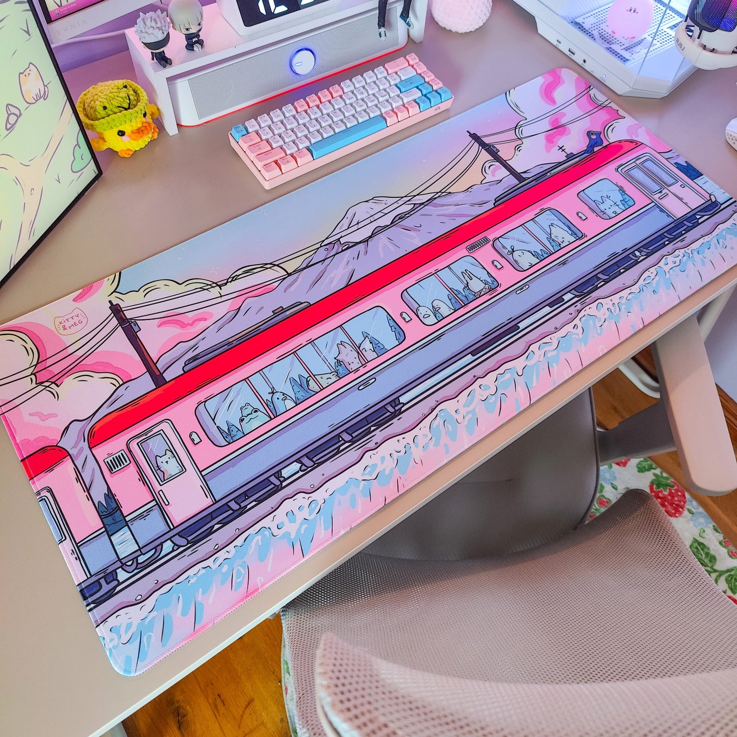 Desk setup with a pink train-themed mouse pad, keyboard, and computer monitor.