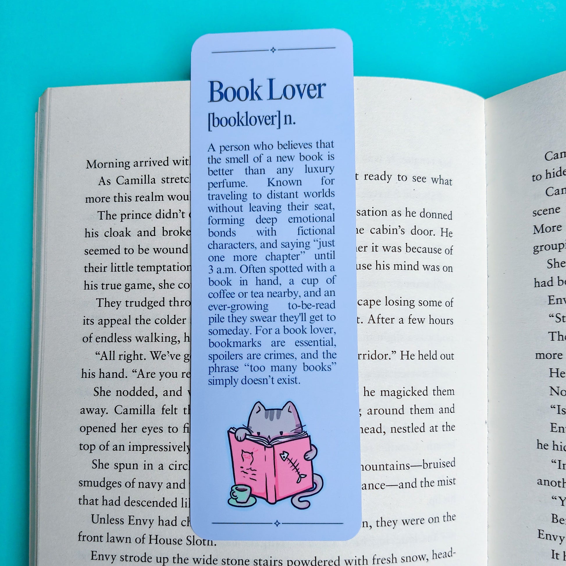 An open book showing printed text and a small pink cartoon character illustration, photographed against a bright blue background.