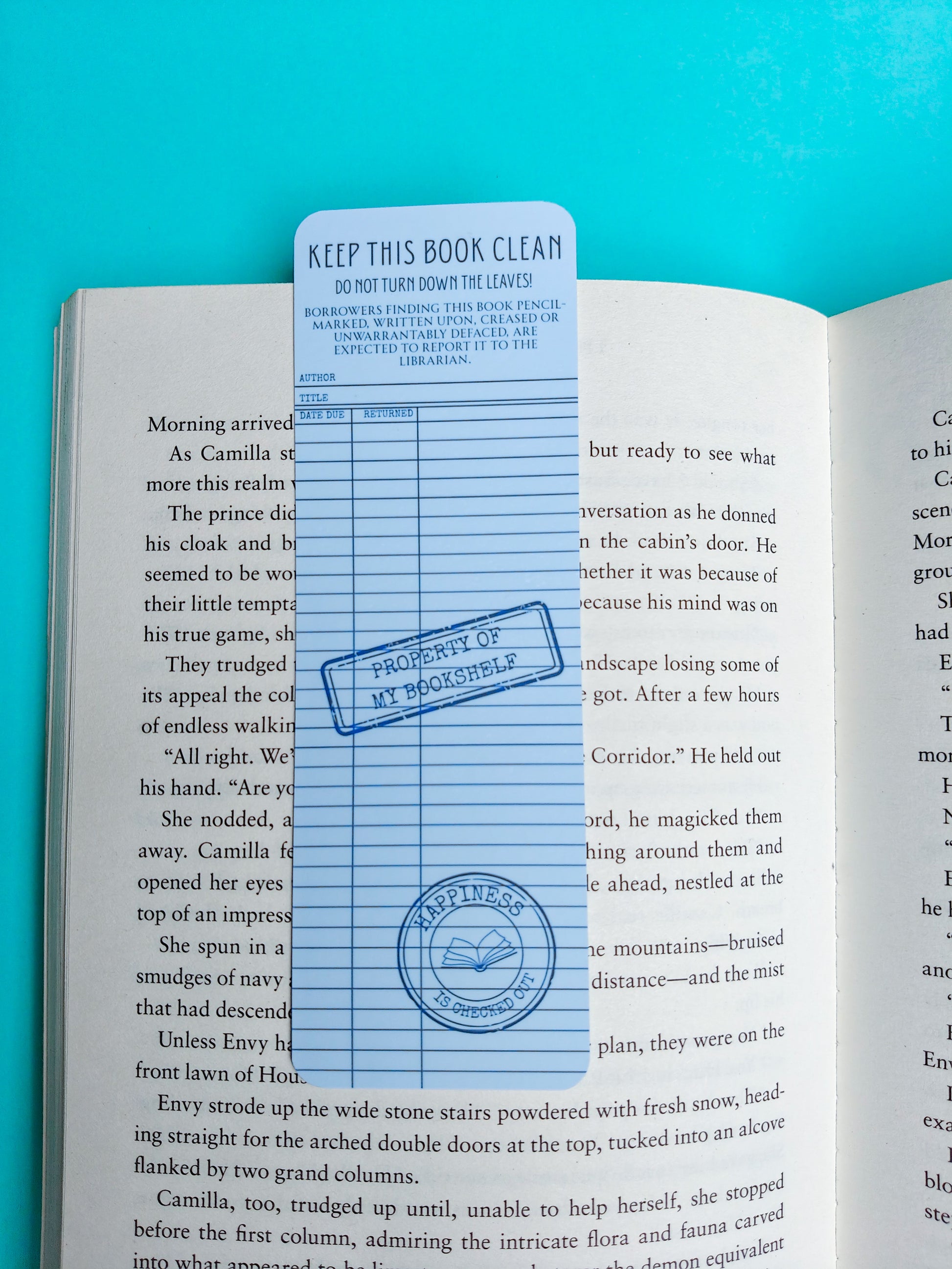 A book cover protector sheet with blue lines and a 'PROPERTY OF MY BOOKSABLE' stamp, shown on an open book against a bright blue background.