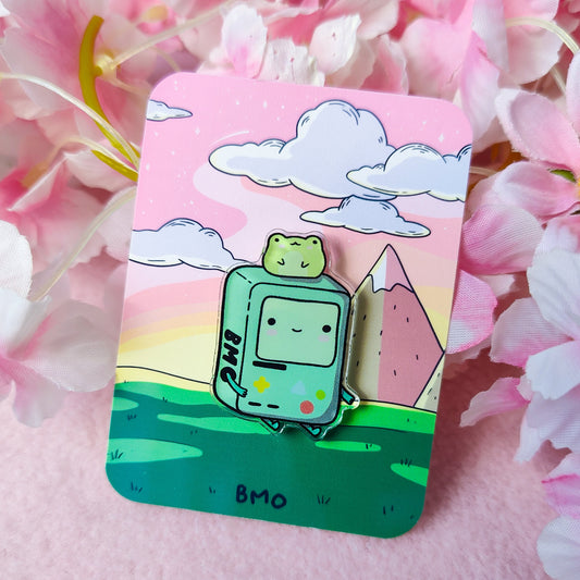 Cute BMO-inspired acrylic pin with a frog on his head, displayed on art backing card