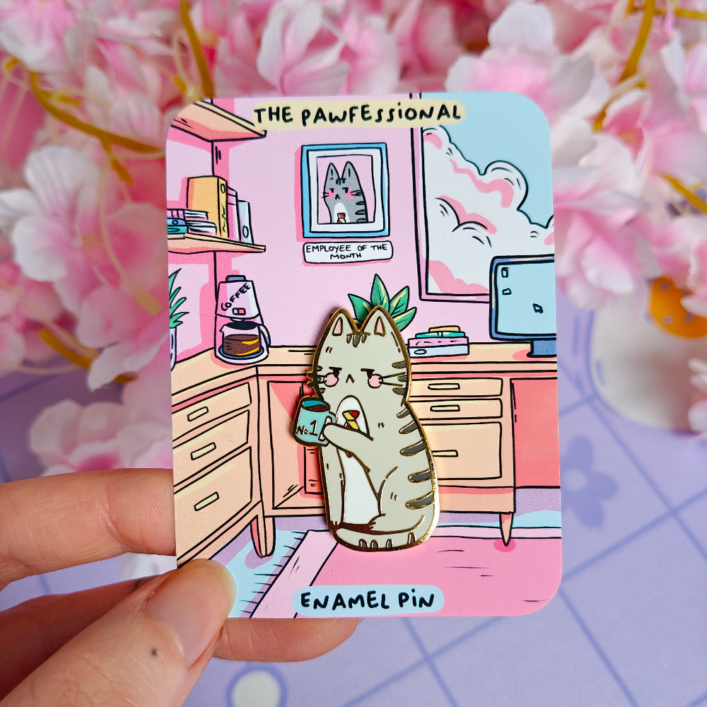 Enamel pin with cartoon cat character in a office setting, held against a pink floral background.