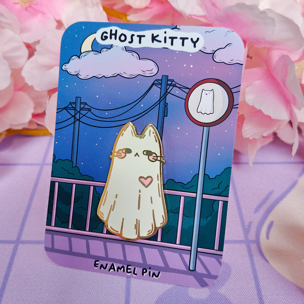 Enamel pin with cartoon ghost cat design on a card, surrounded by pink flowers.